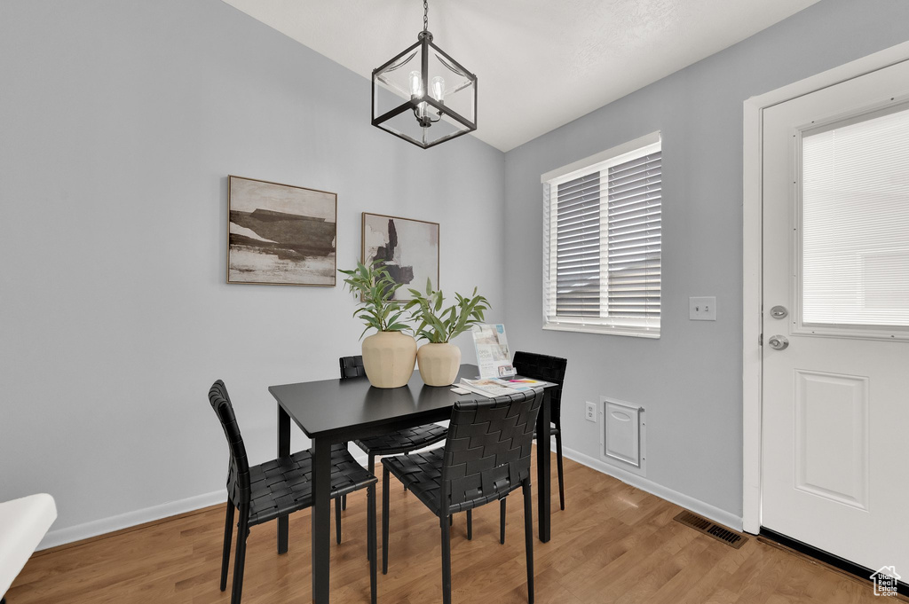 Dining space with a chandelier, light wood-type flooring, and baseboards