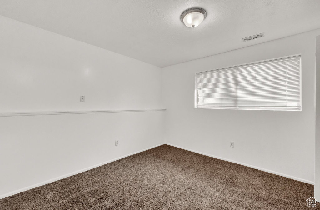 Unfurnished room with dark carpet and baseboards
