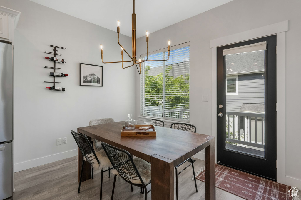 Dining space with light wood-style flooring, a chandelier, healthy amount of natural light, and baseboards