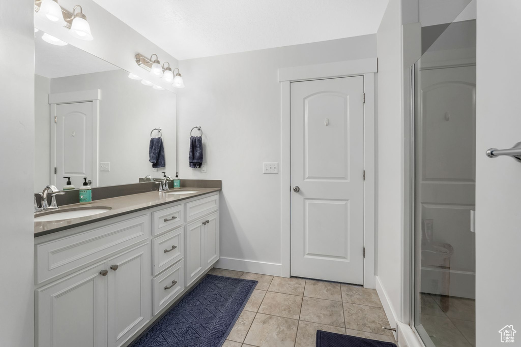 Bathroom with double vanity, tile patterned flooring, and baseboards