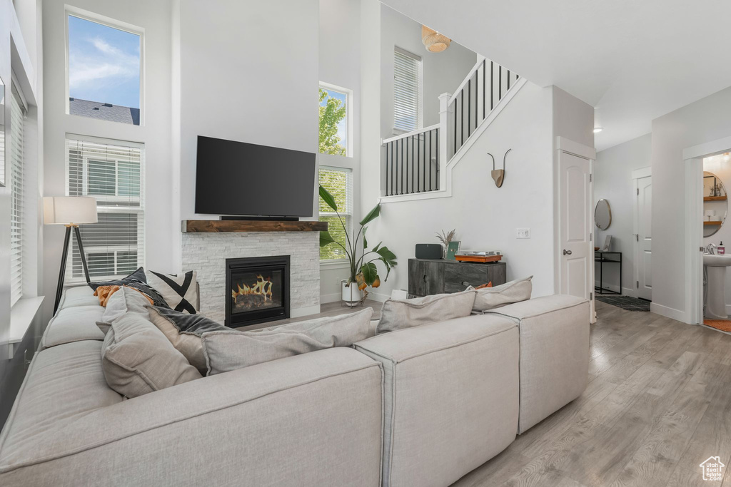 Living area with a towering ceiling, light wood-style floors, a fireplace, and baseboards