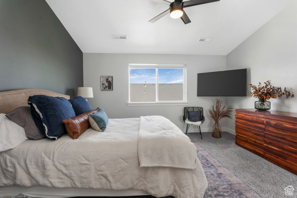 Carpeted bedroom with lofted ceiling, baseboards, and ceiling fan