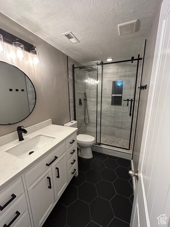 Full bathroom with vanity, a stall shower, toilet, tile patterned floors, and a textured ceiling