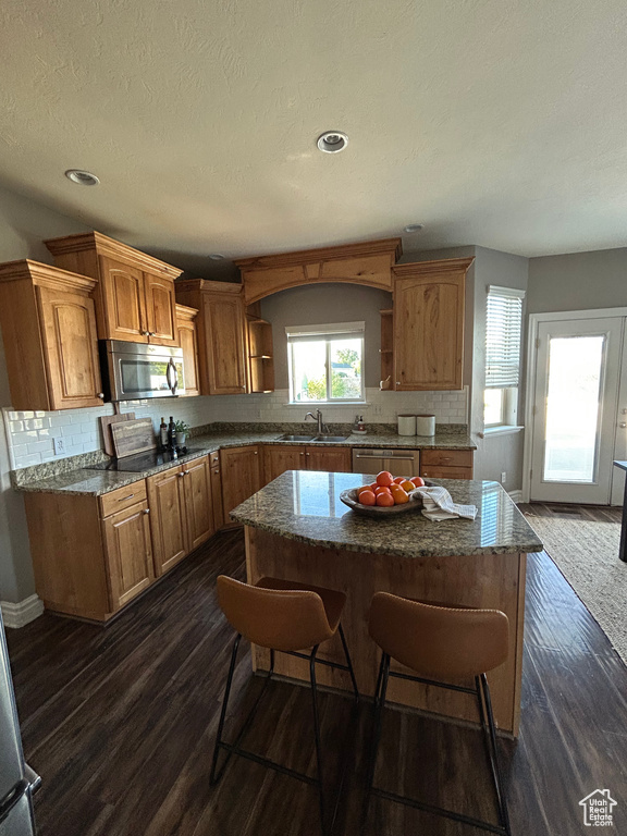 Kitchen featuring open shelves, stainless steel appliances, decorative backsplash, dark wood-type flooring, and a kitchen island