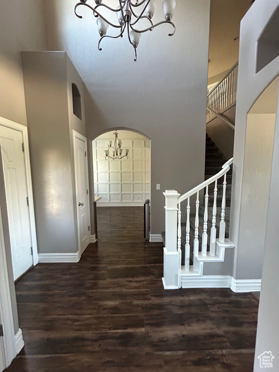 Entryway with a chandelier, a towering ceiling, wood finished floors, and baseboards