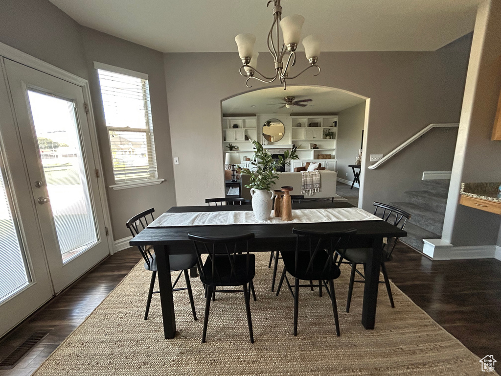 Dining space featuring arched walkways, a chandelier, dark wood-style floors, and baseboards