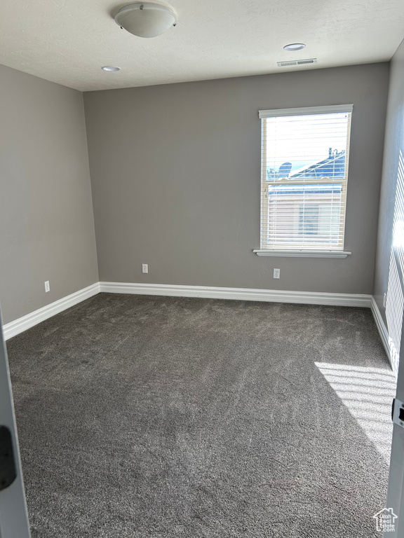 Unfurnished room with dark carpet and baseboards