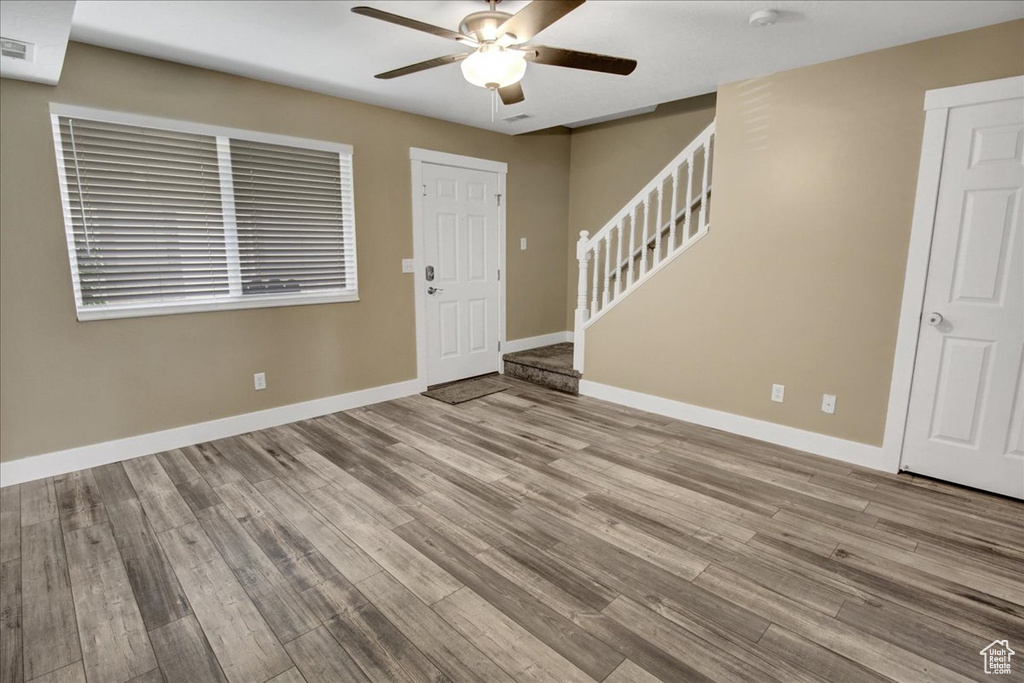 Entryway featuring a ceiling fan, stairway, baseboards, and wood finished floors