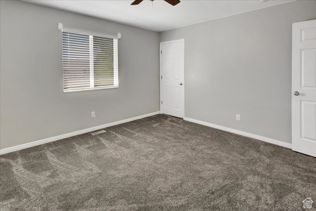 Spare room featuring a ceiling fan, carpet, and baseboards