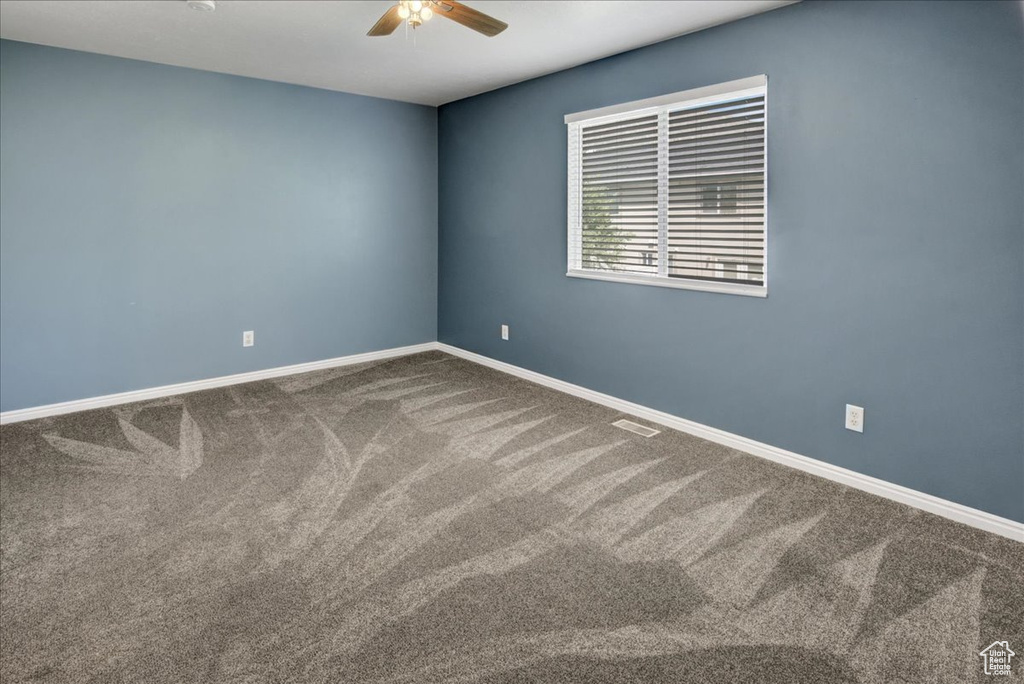 Spare room with a ceiling fan, carpet, and baseboards