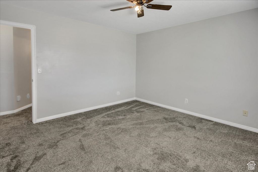 Carpeted spare room with a ceiling fan and baseboards