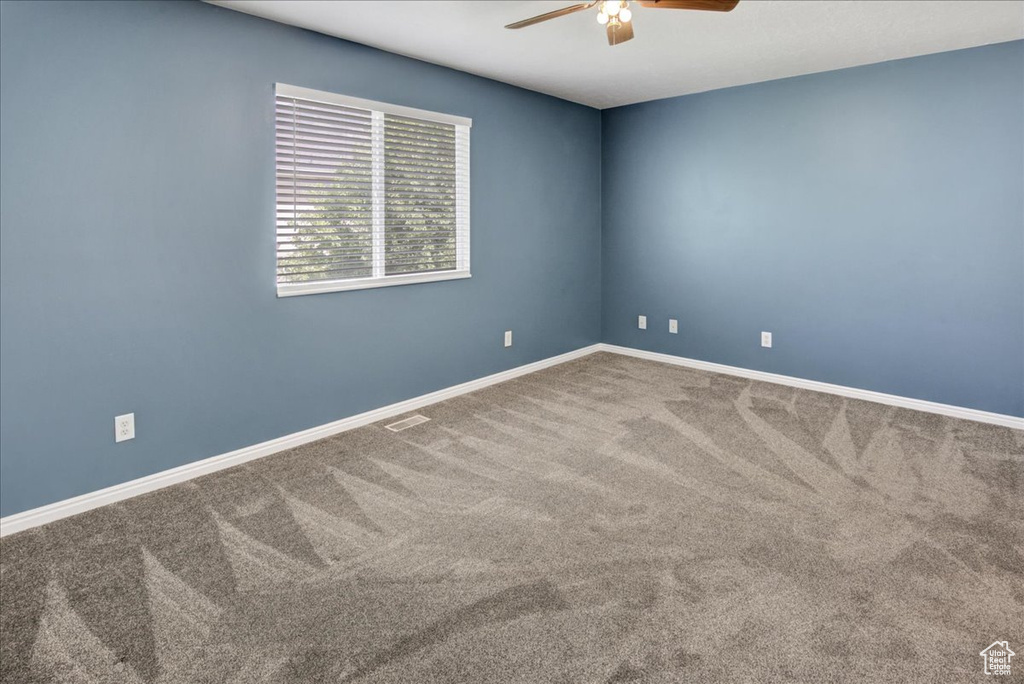 Spare room with a ceiling fan, carpet flooring, and baseboards