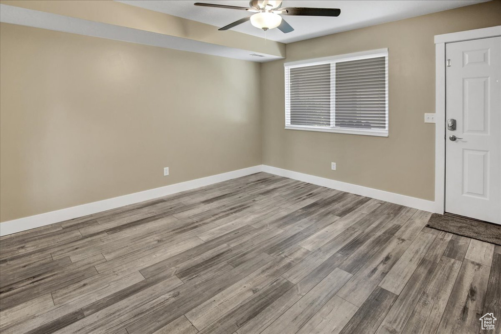 Spare room with a ceiling fan, wood finished floors, and baseboards