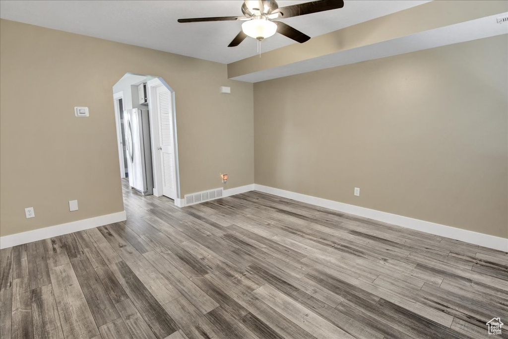 Spare room featuring a ceiling fan, arched walkways, wood finished floors, and baseboards