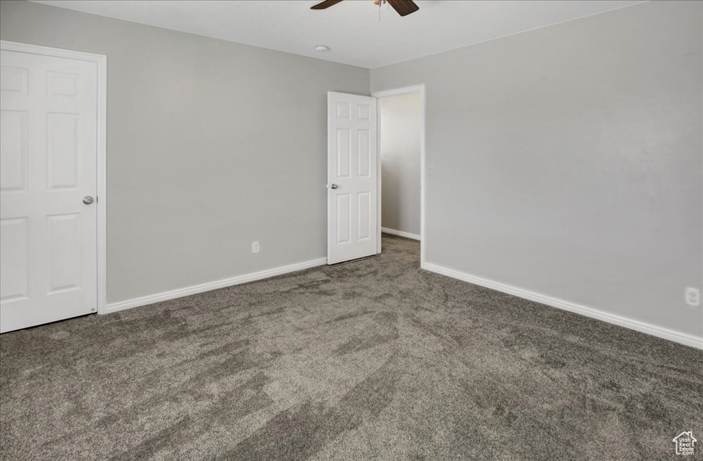 Empty room featuring a ceiling fan, carpet, and baseboards