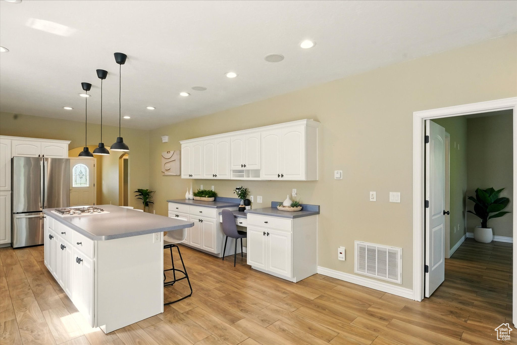 Kitchen with freestanding refrigerator, white cabinetry, light wood-style flooring, and recessed lighting