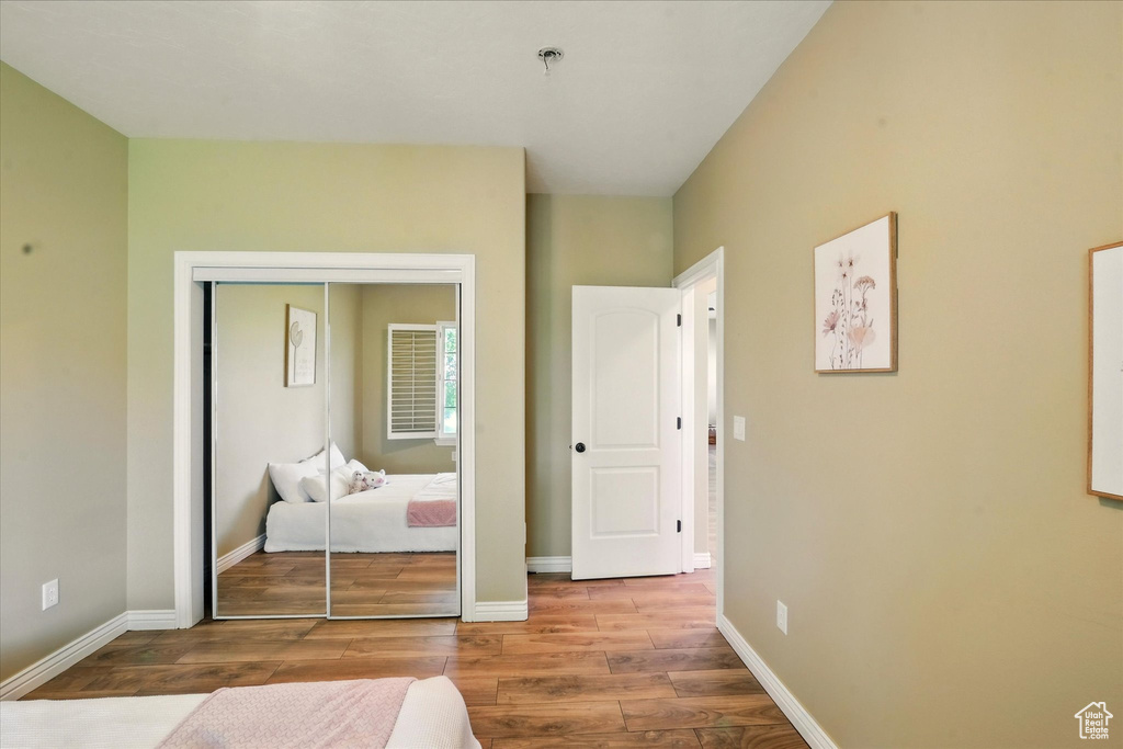 Bedroom with wood finished floors, a closet, and baseboards