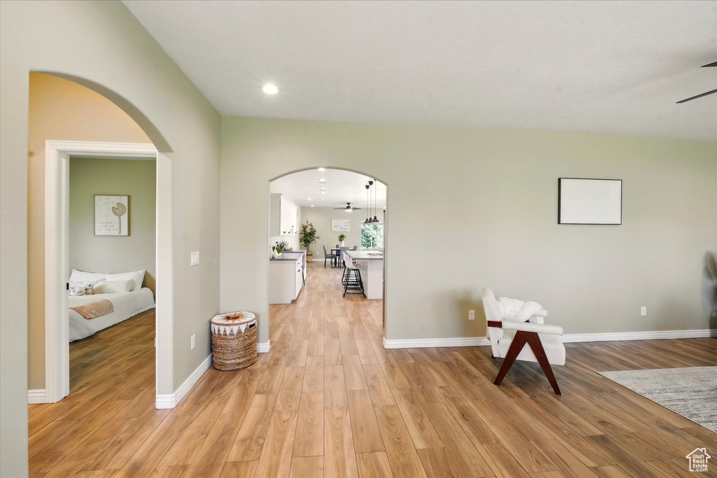 Hall with arched walkways, light wood-style flooring, baseboards, and recessed lighting