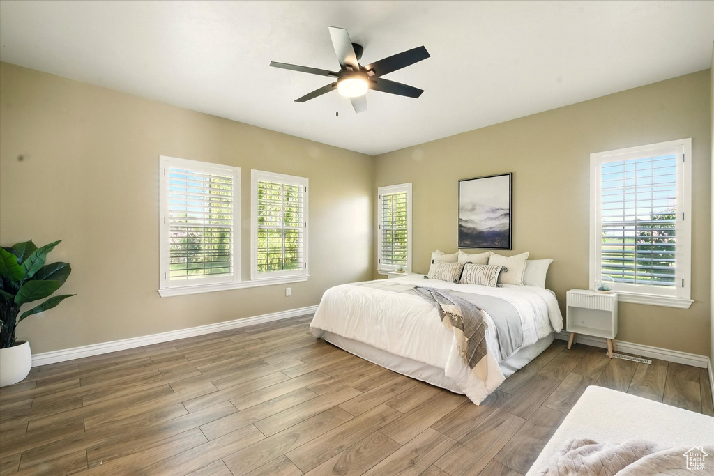 Bedroom featuring baseboards, multiple windows, and wood finished floors