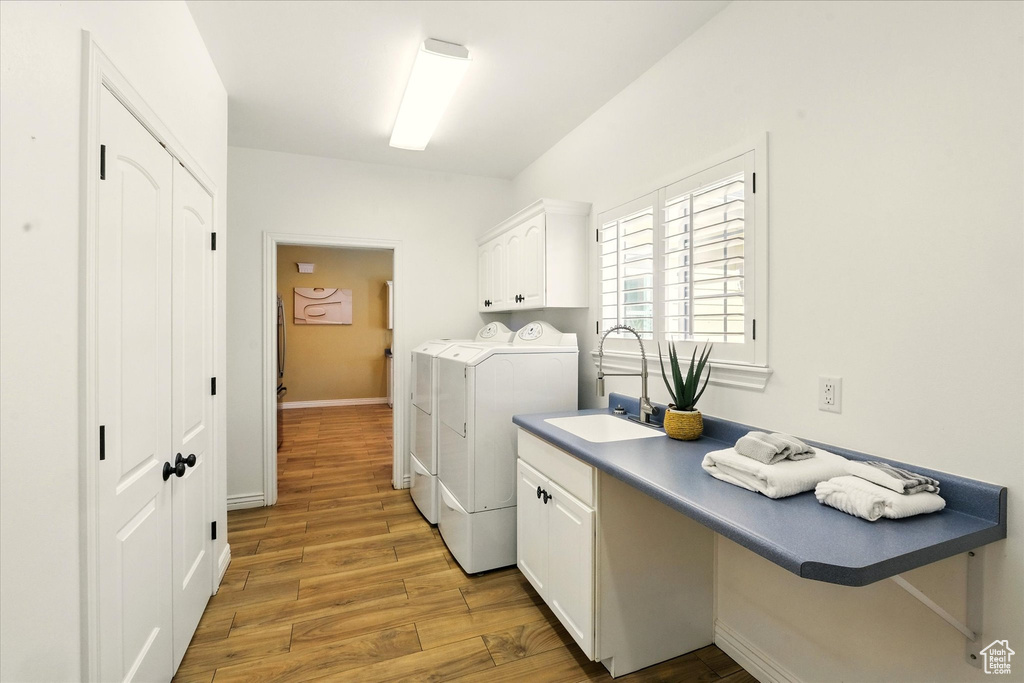 Washroom featuring cabinet space, washing machine and clothes dryer, light wood finished floors, baseboards, and an office area