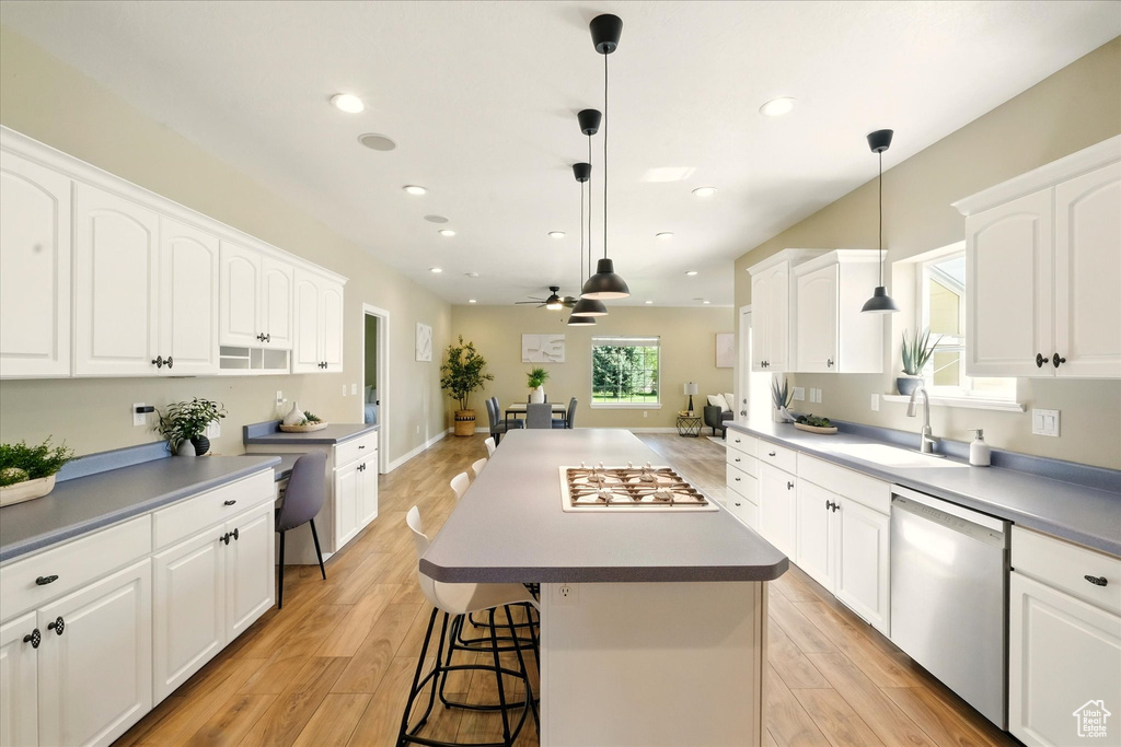 Kitchen with stainless steel dishwasher, a sink, white gas stovetop, ceiling fan, and a center island