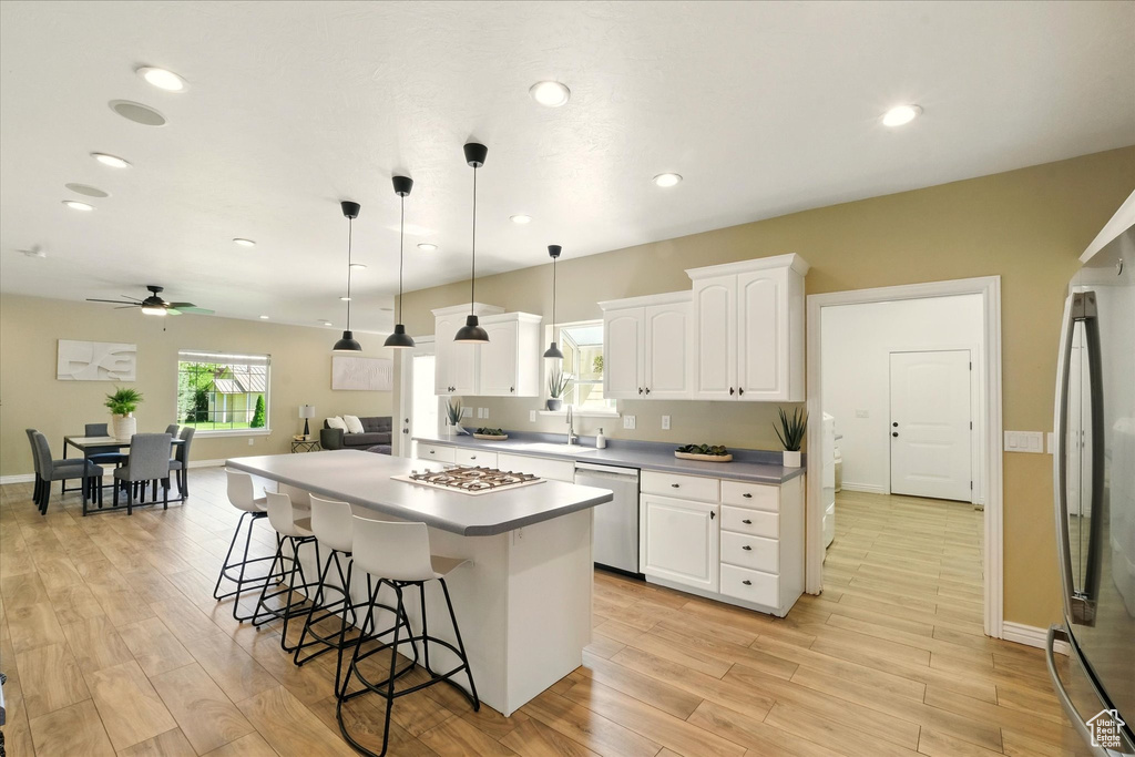 Kitchen featuring appliances with stainless steel finishes, ceiling fan, a kitchen breakfast bar, light wood finished floors, and a sink