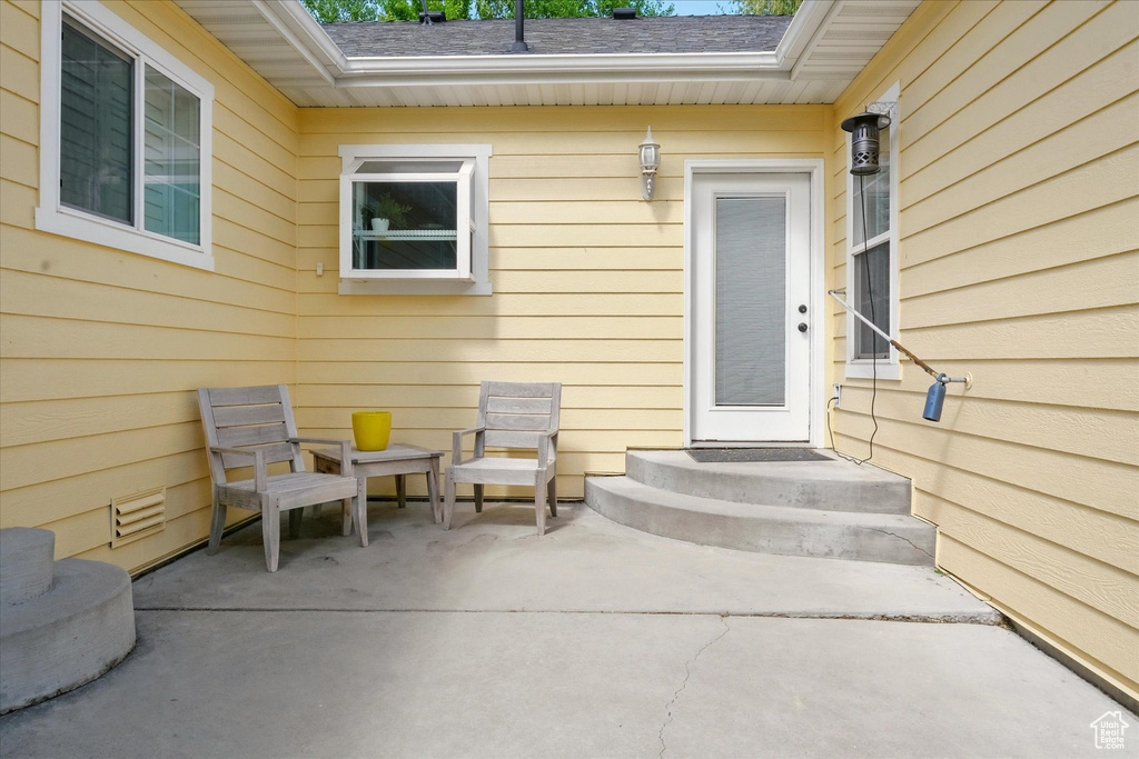 Entrance to property featuring a patio area and roof with shingles
