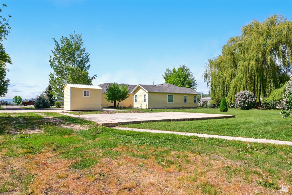 View of side of home with an outdoor structure, a storage unit, and a yard