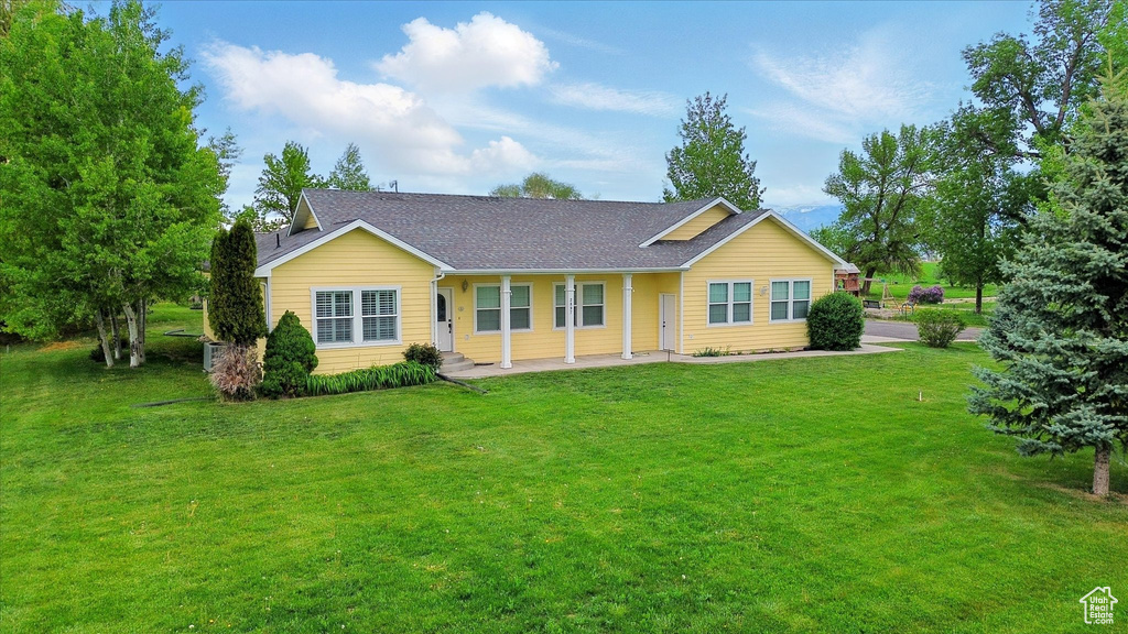 Back of house featuring a yard and a shingled roof