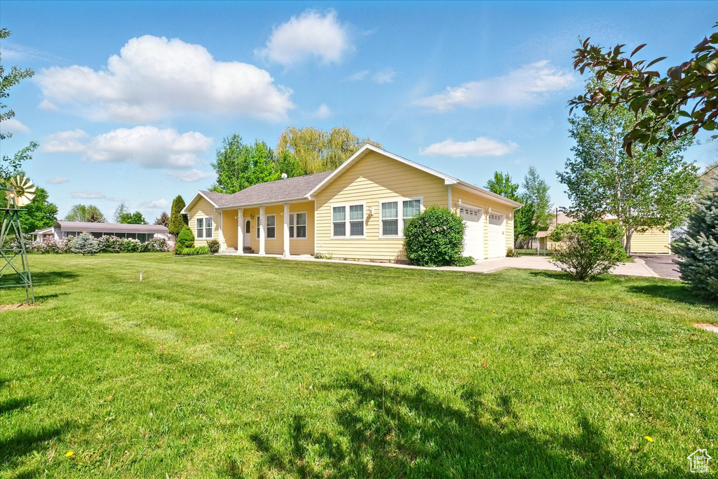 Back of property with a yard, an attached garage, and concrete driveway