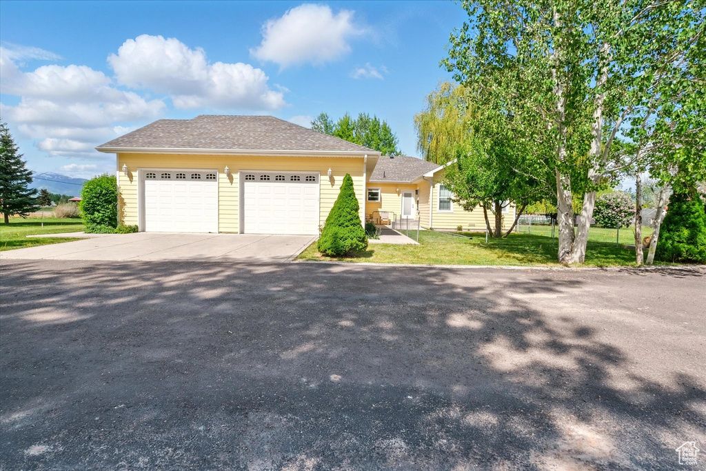 View of front of home featuring a front yard, driveway, and a garage