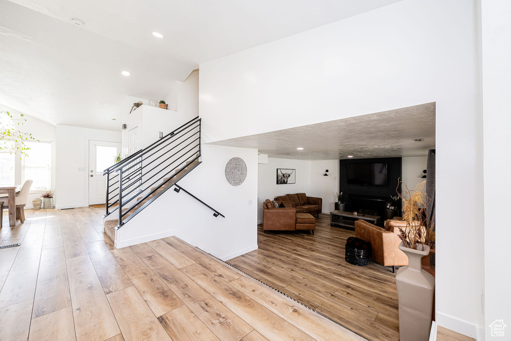 Living room with stairway, light wood-type flooring, baseboards, and recessed lighting