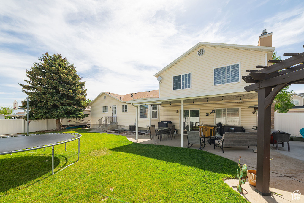 Rear view of house featuring a trampoline, a pergola, a patio, a chimney, and an outdoor living space