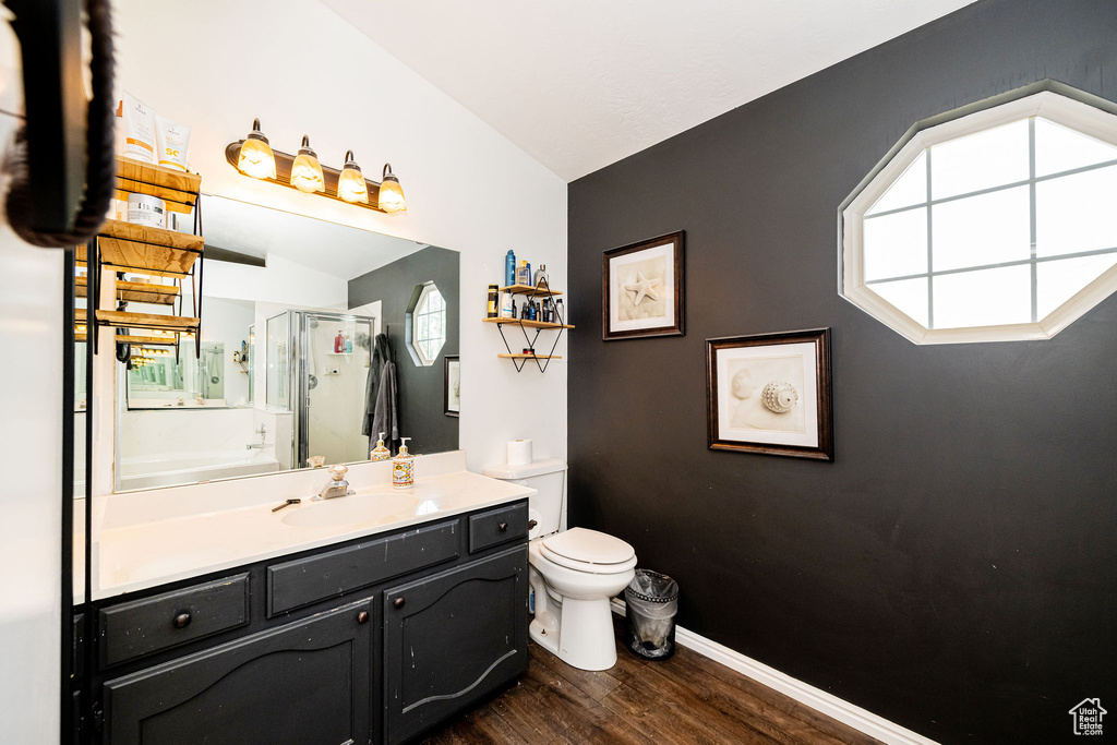 Full bathroom with wood finished floors, a shower stall, toilet, vanity, and baseboards