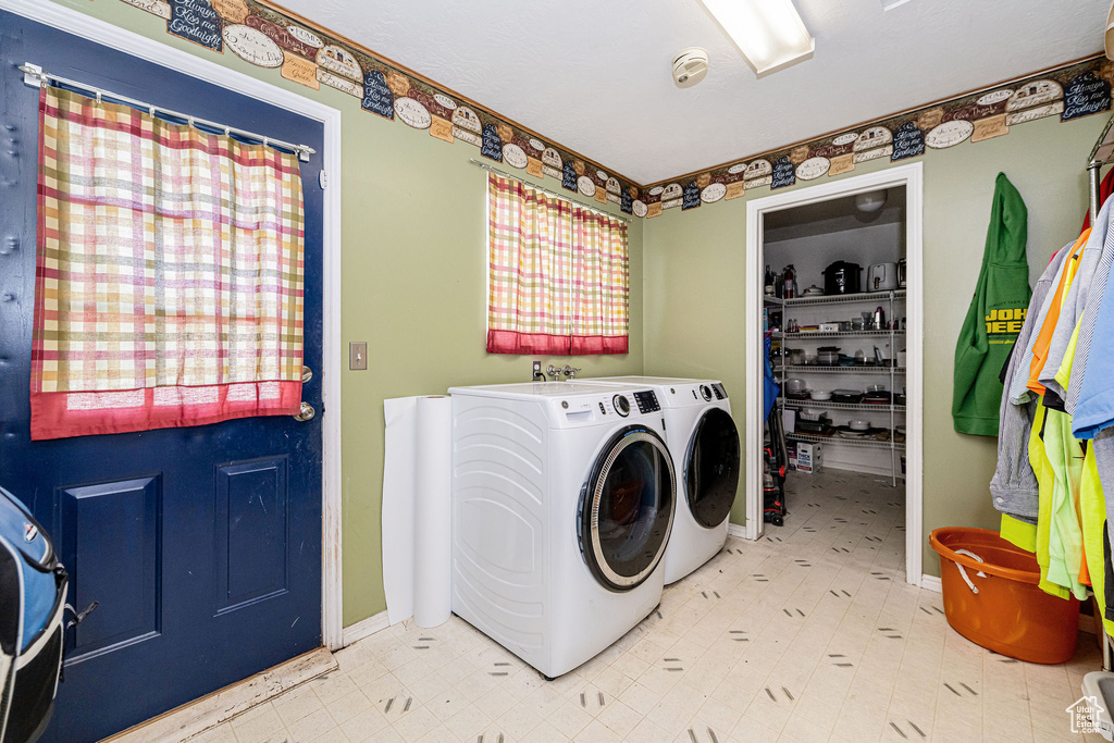 Laundry area featuring washer and clothes dryer, tile patterned floors, and baseboards