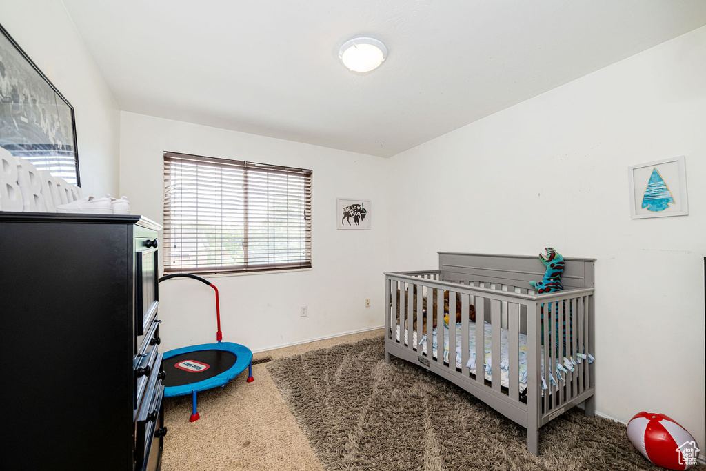 Bedroom with carpet flooring, baseboards, and a nursery area