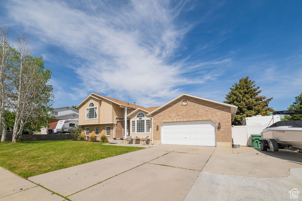 View of front of home featuring brick siding, concrete driveway, an attached garage, and stucco siding