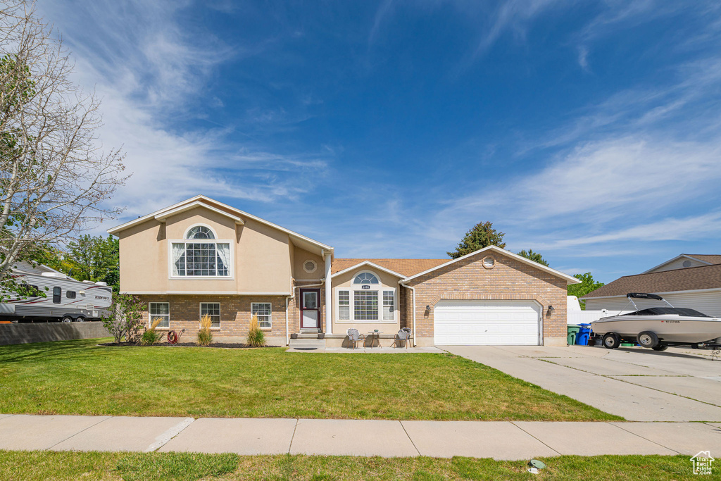 View of front of house featuring brick siding, concrete driveway, a garage, and stucco siding
