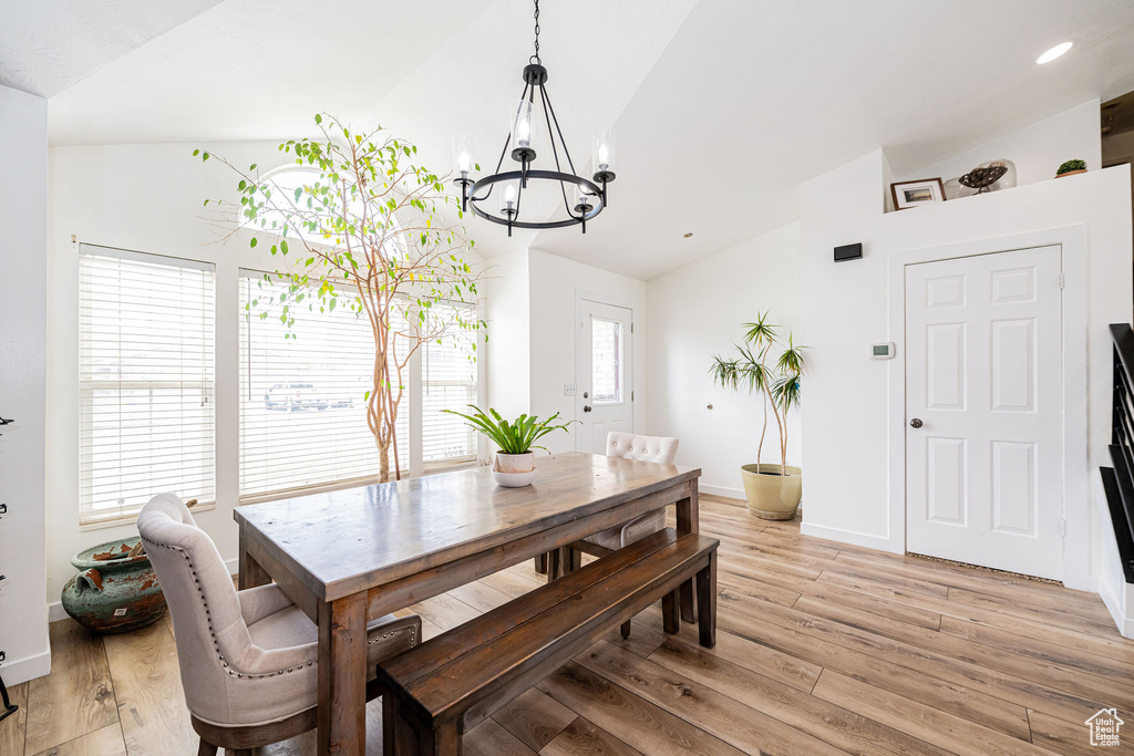 Dining space featuring vaulted ceiling, a chandelier, light wood-type flooring, healthy amount of natural light, and baseboards