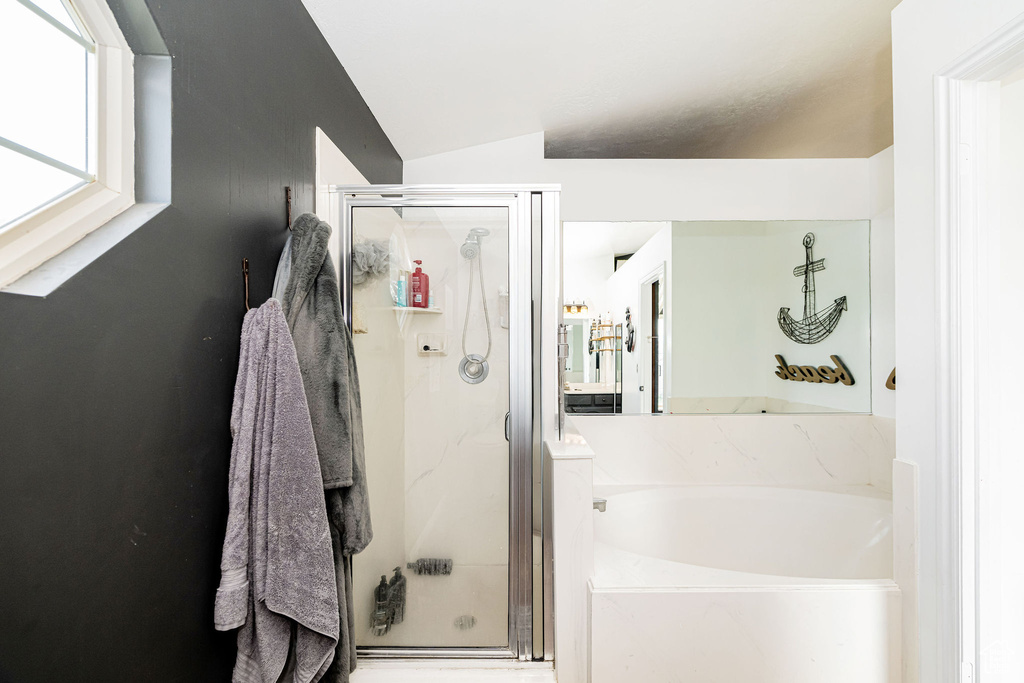 Bathroom featuring a stall shower, a garden tub, and vaulted ceiling