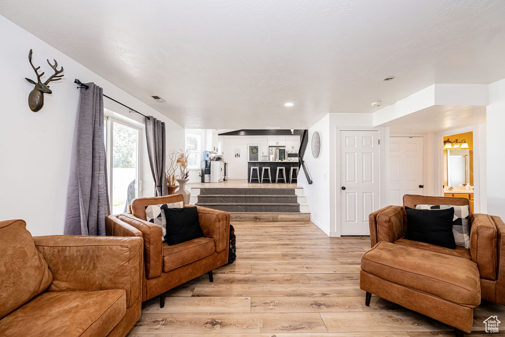 Living area with light wood-style flooring, stairway, and recessed lighting