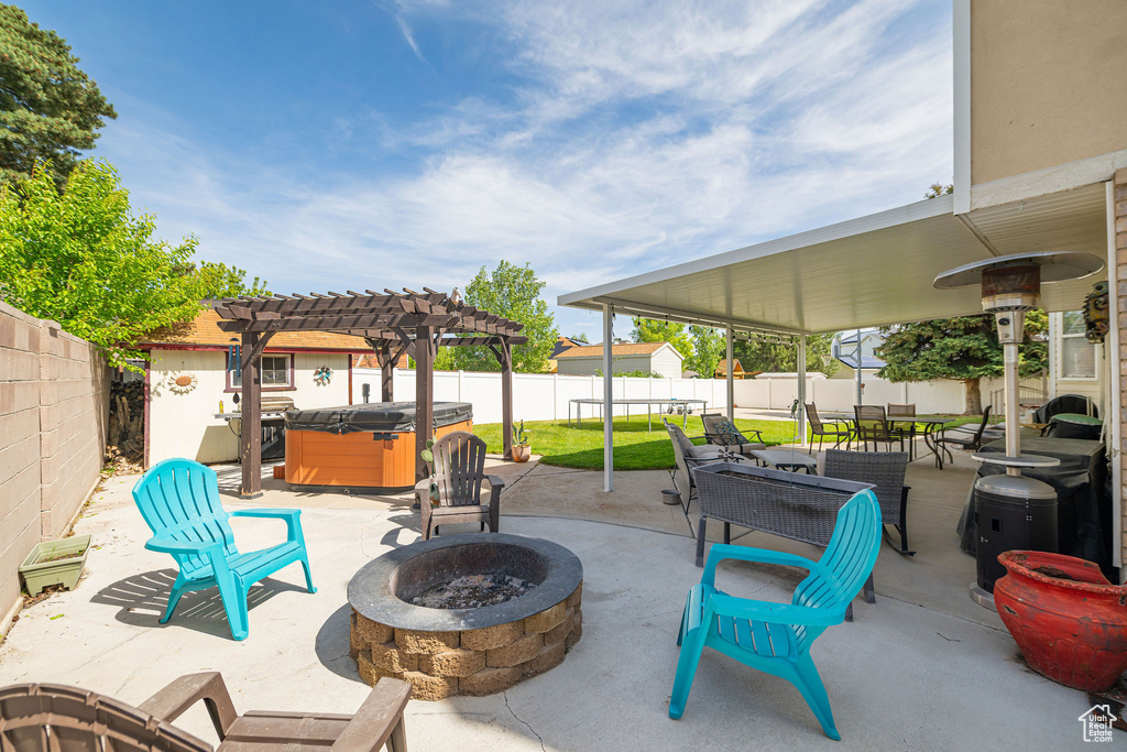 View of patio / terrace with a fire pit, a hot tub, a fenced backyard, and a pergola