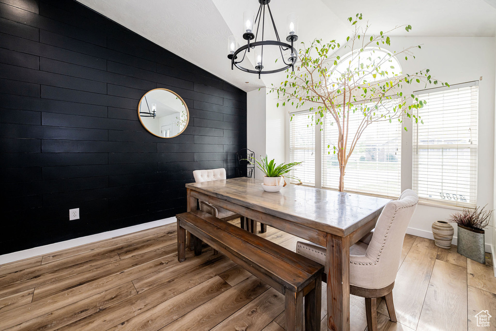 Dining area with lofted ceiling, a chandelier, light wood-style flooring, and baseboards