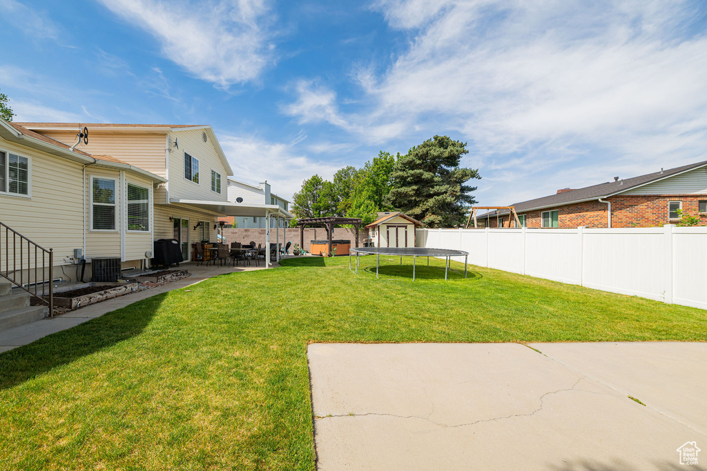 View of yard featuring a trampoline, a patio, and central AC unit