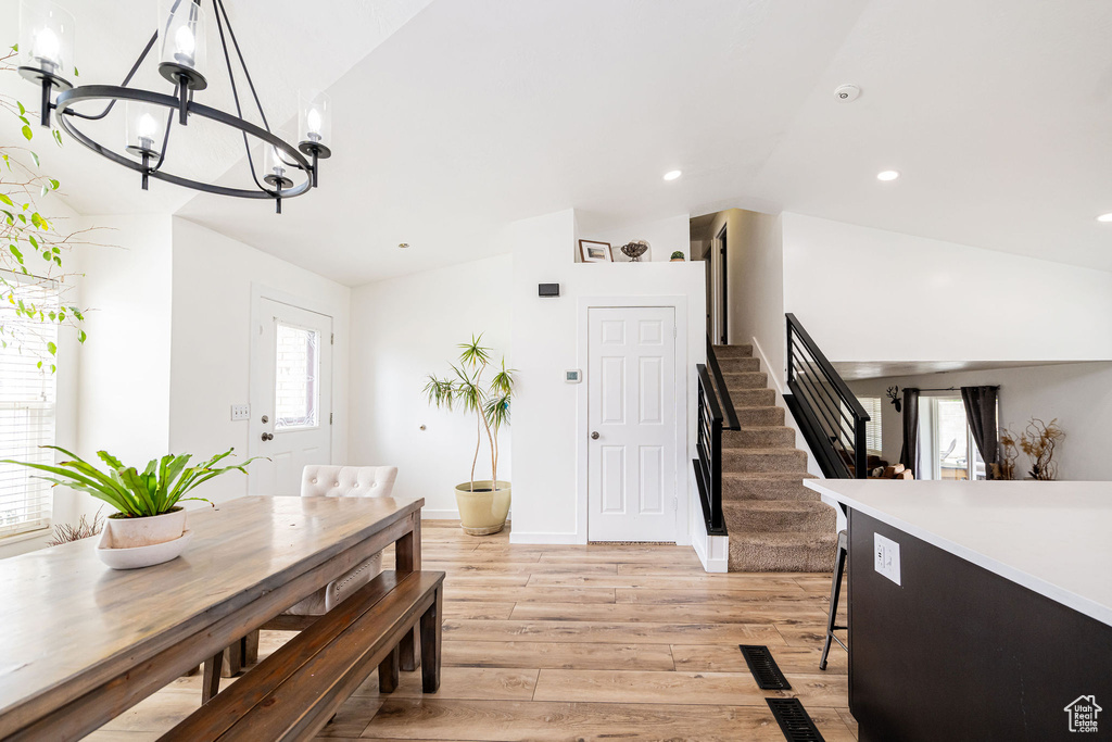 Dining room featuring a chandelier, lofted ceiling, light wood finished floors, stairway, and recessed lighting