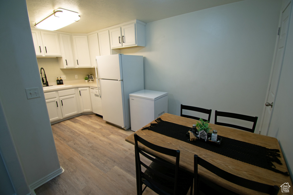 Kitchen featuring freestanding refrigerator, white refrigerator, a sink, and light wood-style flooring