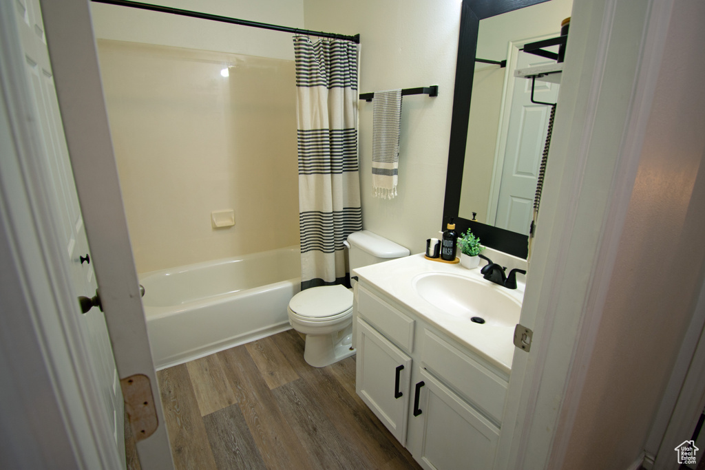 Full bath featuring wood finished floors, toilet, vanity, and shower / bath combo