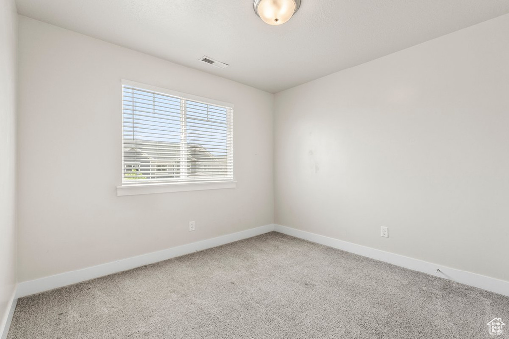 Carpeted spare room featuring baseboards