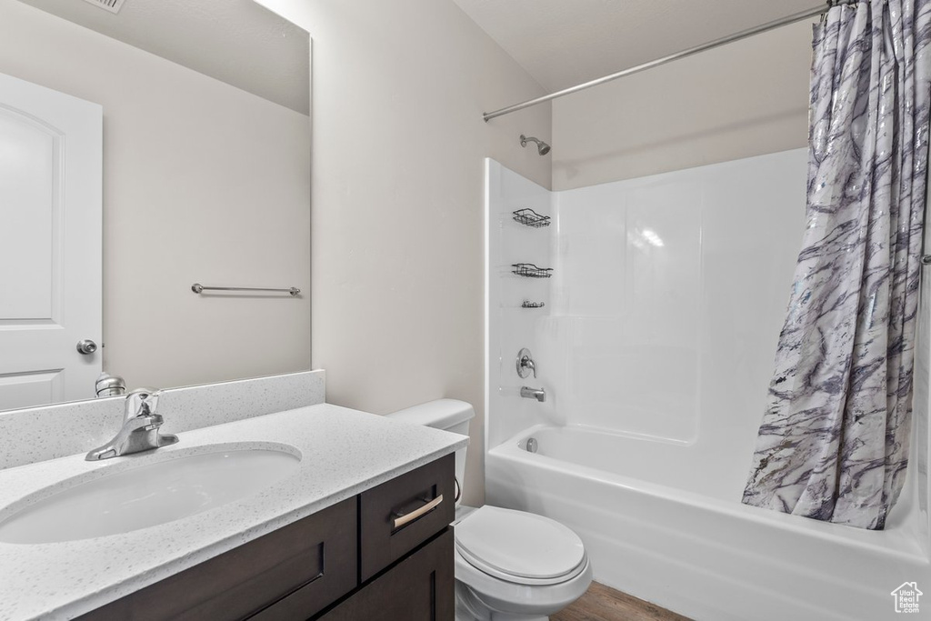 Full bathroom featuring toilet, shower / bath combo, vanity, and wood finished floors