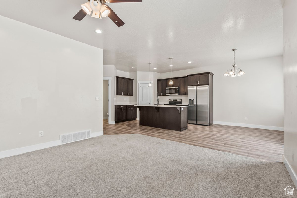 Kitchen with stainless steel appliances, open floor plan, a ceiling fan, dark brown cabinets, and recessed lighting